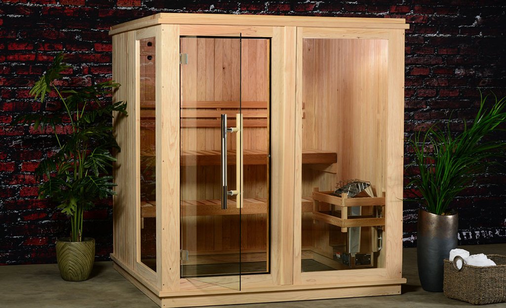 A modern home sauna featuring cedar wood and glass in a bright room.
