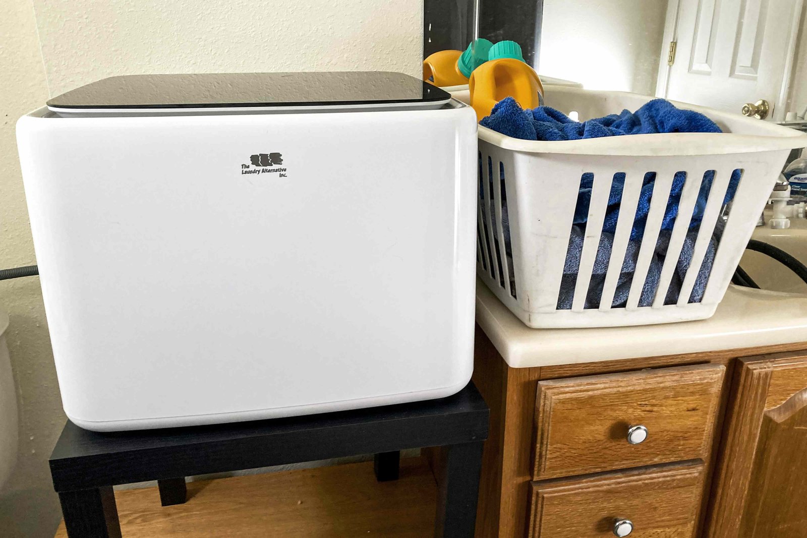 A compact portable washing machine placed in a bright and modern laundry area.