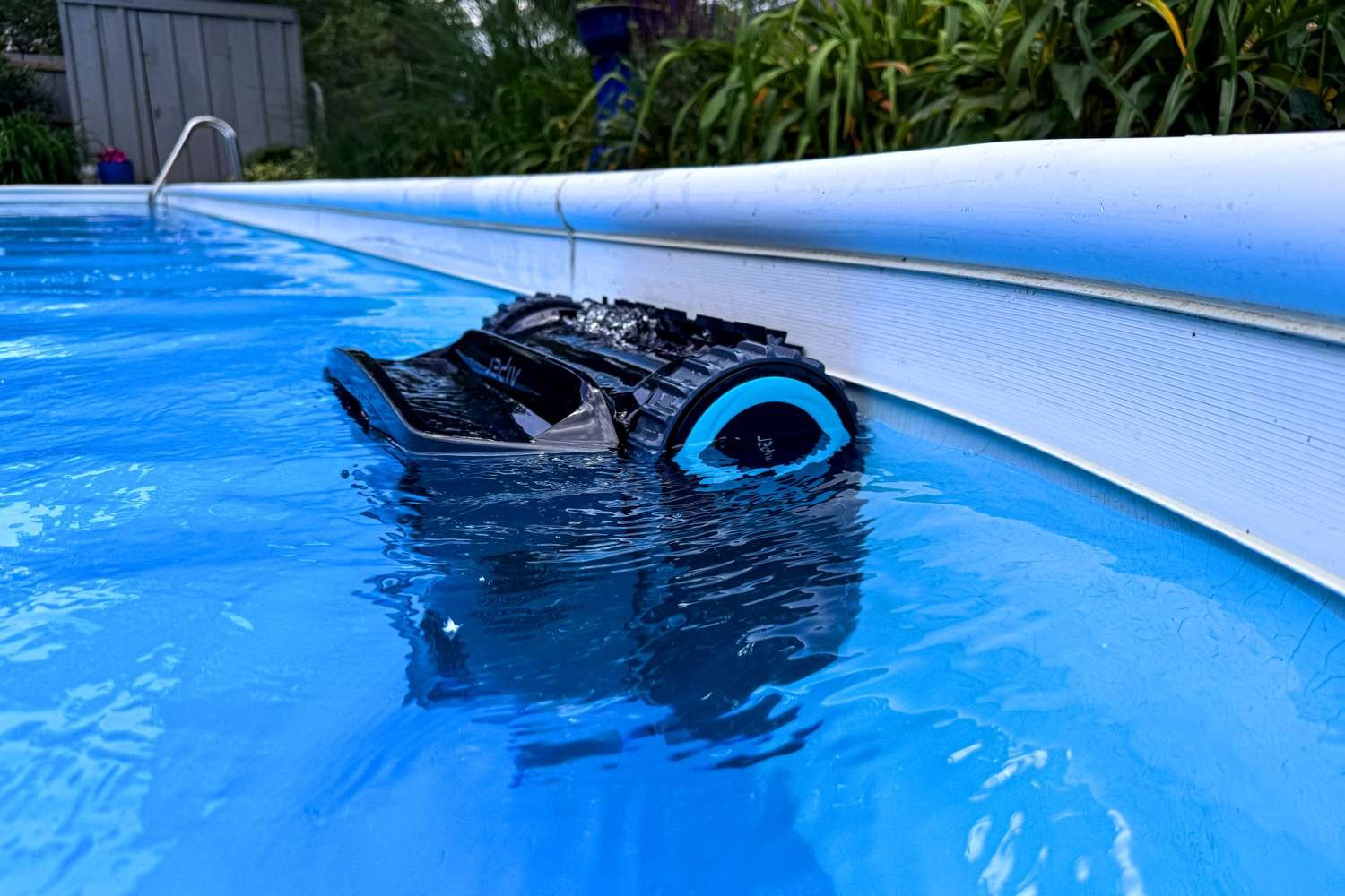 A modern robotic pool cleaner submerged at the bottom of a clear swimming pool.
