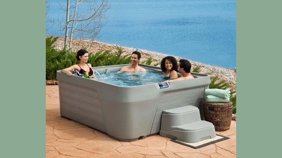 A modern inflatable hot tub sits on a green lawn during a sunset.