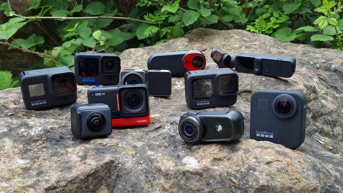 A compact action camera resting on a wooden table near a forest trail.