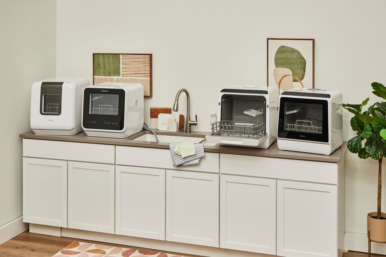 Compact countertop dishwasher on a kitchen counter beside stacked plates and glasses