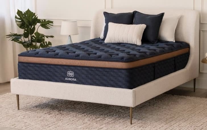 Firm queen hybrid mattress on oak bed frame in a bright bedroom, ideal for back pain