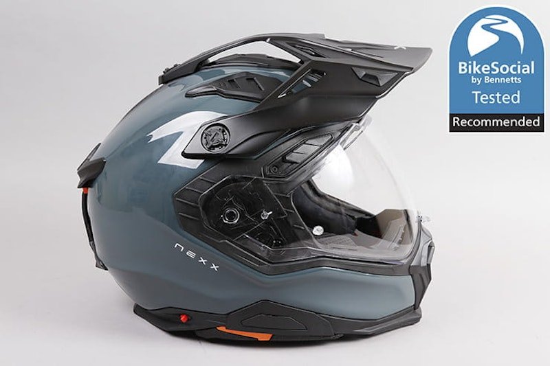 Two motorcycle helmets resting on a wooden bench in a sunlit garage