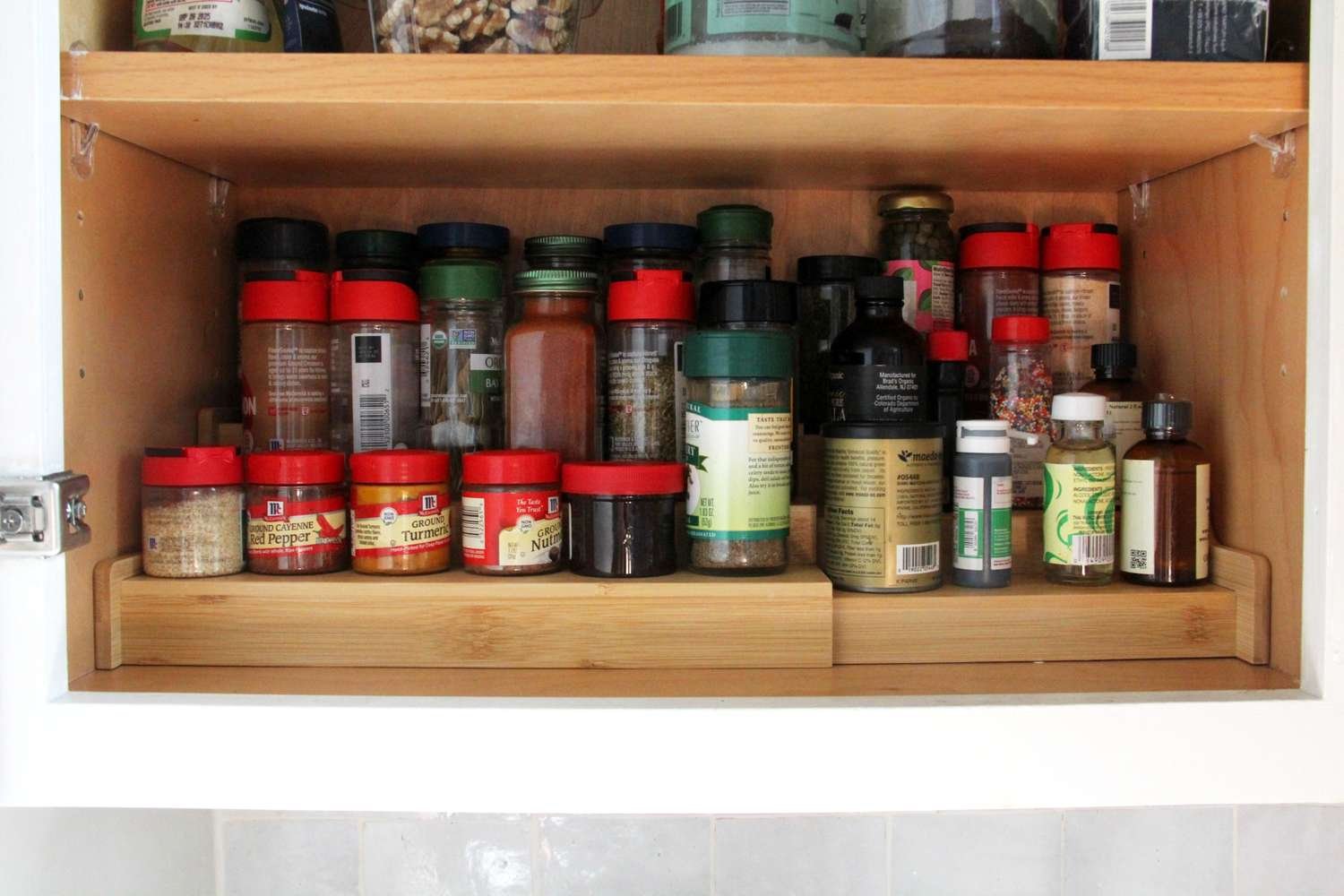 Wooden spice rack holding glass jars of colorful spices on a kitchen counter